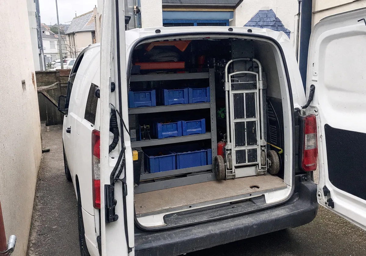 A service van waiting on a long suburban driveway, its tailgate open and the stock bins within reach.